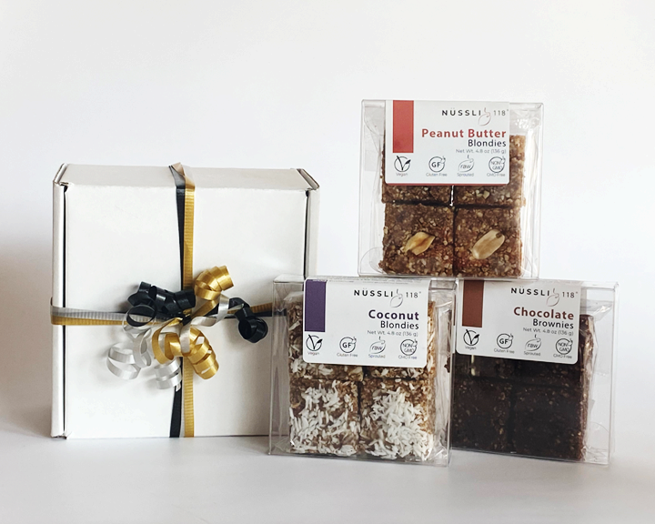 A vegan chocolate brownie and blondie gift box with a colorful label and ribbon on a white background.