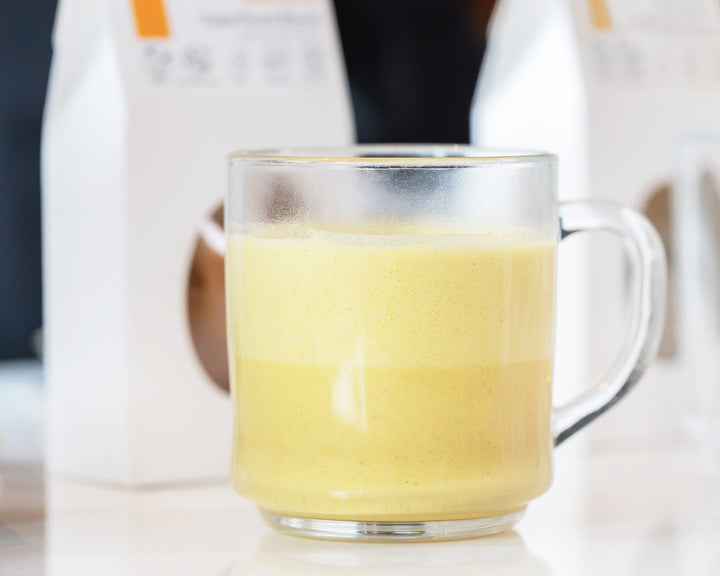 Glass of golden turmeric restore organic superfoods blend with sprouted nuts milk.